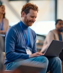 Happy businessman using laptop during a seminar in convention center.