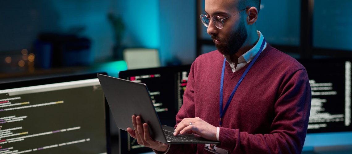 Bearded Man Holding Laptop in Cybersecurity Office