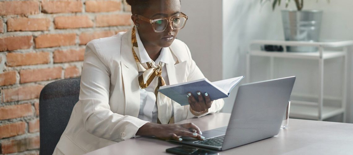 Black businesswoman working on laptop at corporate office.