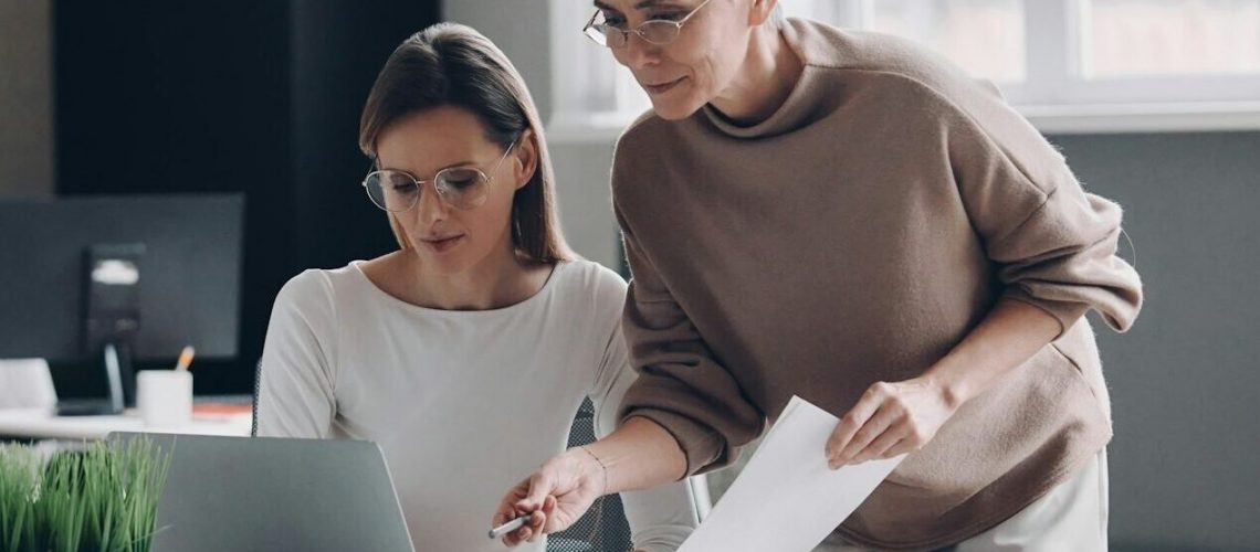 Two confident businesswomen looking at computer monitor while working in the office together